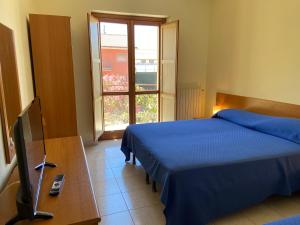 een slaapkamer met 2 bedden, een tv en een raam bij Hotel Mercure in Castelluccio Inferiore