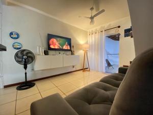 a living room with a couch and a flat screen tv at Casa Aconchego 5min do centro histórico e praia in Paraty