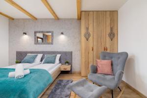 a bedroom with a bed and a chair at Premium Apartments Salwatoriańska Mountain View Zakopane by Renters Prestige in Zakopane