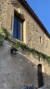 a stone building with a window and a lamp at Domaine de la Reynaude in Aurons