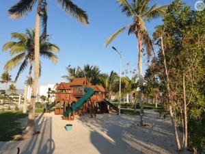 - une aire de jeux avec toboggan dans un parc planté de palmiers dans l'établissement NOOR PLAZA BEACH FURNISHED FLATS, à Salalah