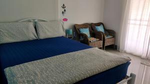 a bedroom with a blue bed and two wicker chairs at บ้านพักวิตามินซี จันทบุรี in Chao Lao Beach