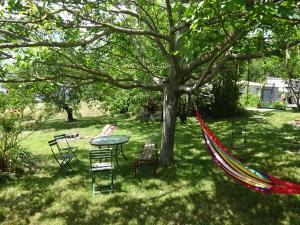 einen Tisch und Stühle unter einem Baum mit Hängematte in der Unterkunft Maison de charme à Saoû, avec beau jardin au calme in Saou