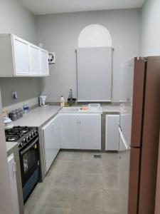 a white kitchen with a stove and a refrigerator at The Blue Gate 6 in Muscat