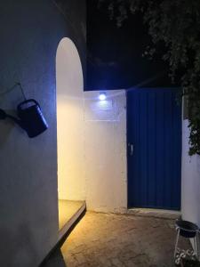 a blue door on a white wall with a light at The Blue Gate 6 in Muscat