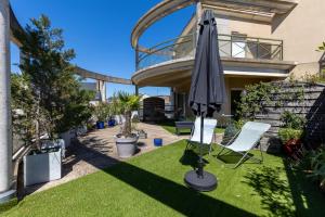 une terrasse avec un parasol et des chaises sur la pelouse dans l'établissement Le Roof Top - Centre ville - Double garage - 6p, au Mans