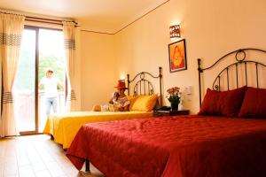 a woman walking into a hotel room with two beds at Hotel Danibaan in Oaxaca City