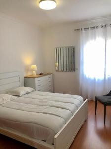 Un dormitorio blanco con una cama grande y una ventana. en Azores Terrace Apartment T2, en Ponta Delgada