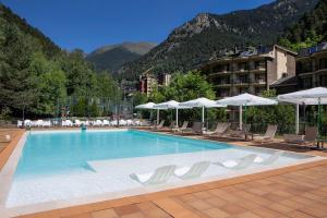 una gran piscina con sillas y sombrillas en Hotel Sant Gothard en Arinsal