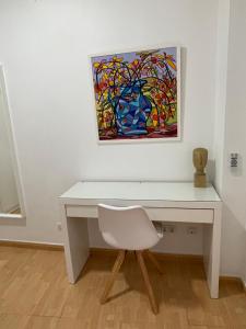 een wit bureau met een witte stoel en een schilderij bij Piso de 2 habitaciones a 200 metros de la playa in Las Palmas de Gran Canaria