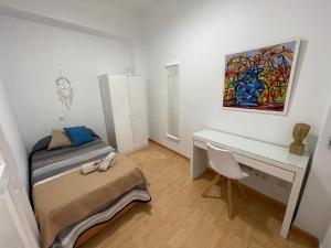 een slaapkamer met een bed, een bureau en een schilderij bij Piso de 2 habitaciones a 200 metros de la playa in Las Palmas de Gran Canaria