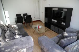 a living room with two couches and a flat screen tv at cosy 3-bed bungalow nec airport close to amenities in Birmingham