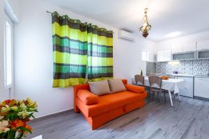 a living room with an orange couch and a kitchen at Apartment Fiorenini in Mlini