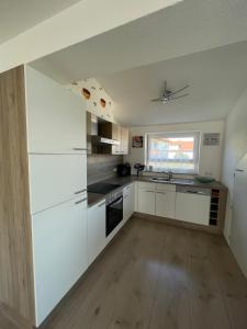 an empty kitchen with white cabinets and a window at Ferienwohnung in Lonsee-Ettlenschieß in Lonsee