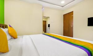 a white bed with a rainbow blanket on it at Itsy By Treebo - Carnival Inn in Nagpur