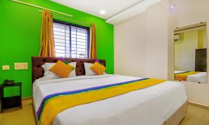 a bedroom with a large bed with a green wall at Itsy Hotels Carnival Inn in Nagpur