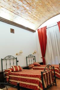 two beds in a room with red sheets at Concordia Rooms B&B in Crotone