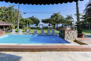a swimming pool with chairs and a fire place at Indaiá Praia Hotel in Bertioga