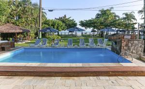 a swimming pool with chairs and a table at Indaiá Praia Hotel in Bertioga