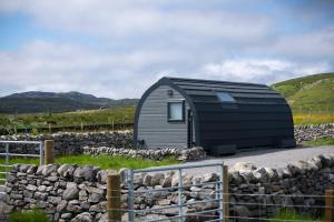 a small black shed with a stone wall at 21 Callanish Luxury Pod in Callernish