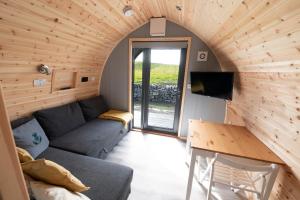 een woonkamer met een grijze bank in een houten kamer bij 21 Callanish Luxury Pod in Callernish