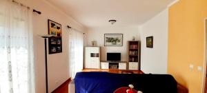 a living room with a blue bed and a television at Casa Olhos de Mar - 7 min pé Praia in Peniche