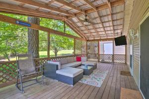 a screened in porch with a couch and a tv at Noteworthy Cabin Grill, Walk to Beaver Lake! in Rogers