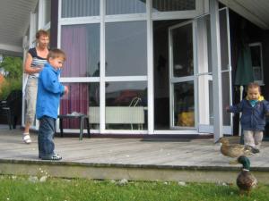 zwei Kinder stehen auf einer Veranda mit zwei Enten in der Unterkunft 6 person holiday home in Otterndorf in Otterndorf