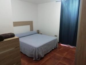 1 dormitorio con cama y cortina azul en Piso El Jardin en Corralejo