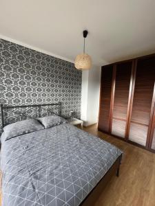 a bedroom with a bed with a gray comforter at Apartament Slupsk in Słupsk