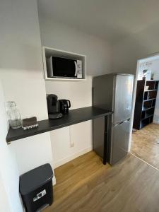a kitchen with a black counter and a refrigerator at Appartement T1 Confort Tête d'Or Doua - Parking Gratuit in Villeurbanne