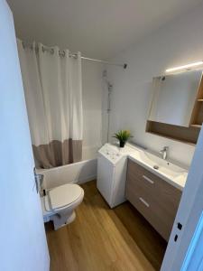 a white bathroom with a toilet and a sink at Appartement T1 Confort Tête d'Or Doua - Parking Gratuit in Villeurbanne