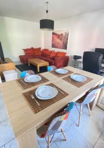 einen Holztisch mit Tellern darauf im Wohnzimmer in der Unterkunft Apt familial quartier Fontonne à Antibes by Weekome in Antibes