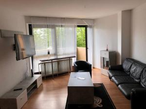 a living room with a black couch and a tv at Ruhige und erholsame Wohnung mit Balkon in Göttingen