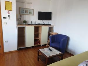 a living room with a tv and a blue chair at Apartment Laguna 70 in Izola