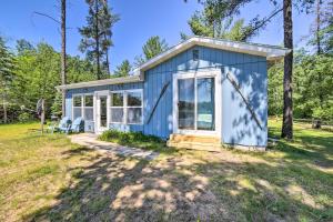 a blue tiny house in a field at Lakefront Wisconsin Cottage with Dock and Hot Tub! in Crivitz
