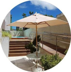 a table with an umbrella in front of a pool at Residence 207 Cabo Branco in João Pessoa