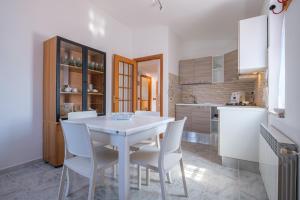 cocina con mesa blanca y sillas blancas en Casa vacanza puro relax, en Capo dʼOrlando