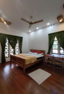 Schlafzimmer mit einem Bett, einem Tisch und Fenstern in der Unterkunft Moon Homestay in Santhanpara