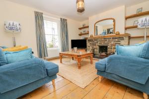 a living room with two blue couches and a fireplace at 1 Dormer Villas in Porthscatho