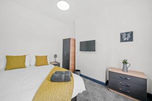 a bedroom with a bed with a dresser and a tv at Modern Equipped 4 BR House in Central Stoke-Free Parking in Stoke on Trent