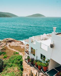 una casa blanca con plantas a un lado del océano en Casa Grega, en Arraial do Cabo