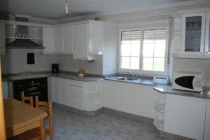 a kitchen with white cabinets and a sink and a table at Casa Farruquitas in Cervo