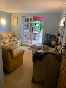 een woonkamer met een bank en een televisie bij Forsythia cottage with surf and cycle hire in Wrafton