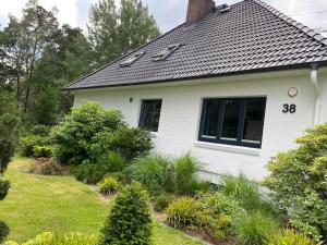 uma casa branca com um telhado preto em 38 Waldweg em Bendestorf