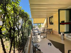 un patio al aire libre con mesas, sillas y árboles en Hotel Al Castello, en Torri del Benaco