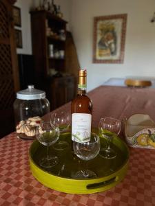 una bottiglia di vino su un vassoio con tre bicchieri di vino di Villa Terreforti a San Pier Niceto