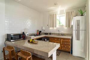a kitchen with a counter with a sink and a refrigerator at Loft Grécia In in Arraial do Cabo