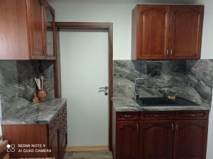 eine Küche mit Holzschränken, einem Waschbecken und einer Tür in der Unterkunft Éva Vendégház in Cserszegtomaj