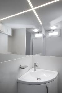 a white bathroom with a sink and a mirror at Homey Experience - Marina Loft in La Maddalena
